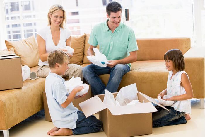 A family wrapping household items and packing moving boxes
